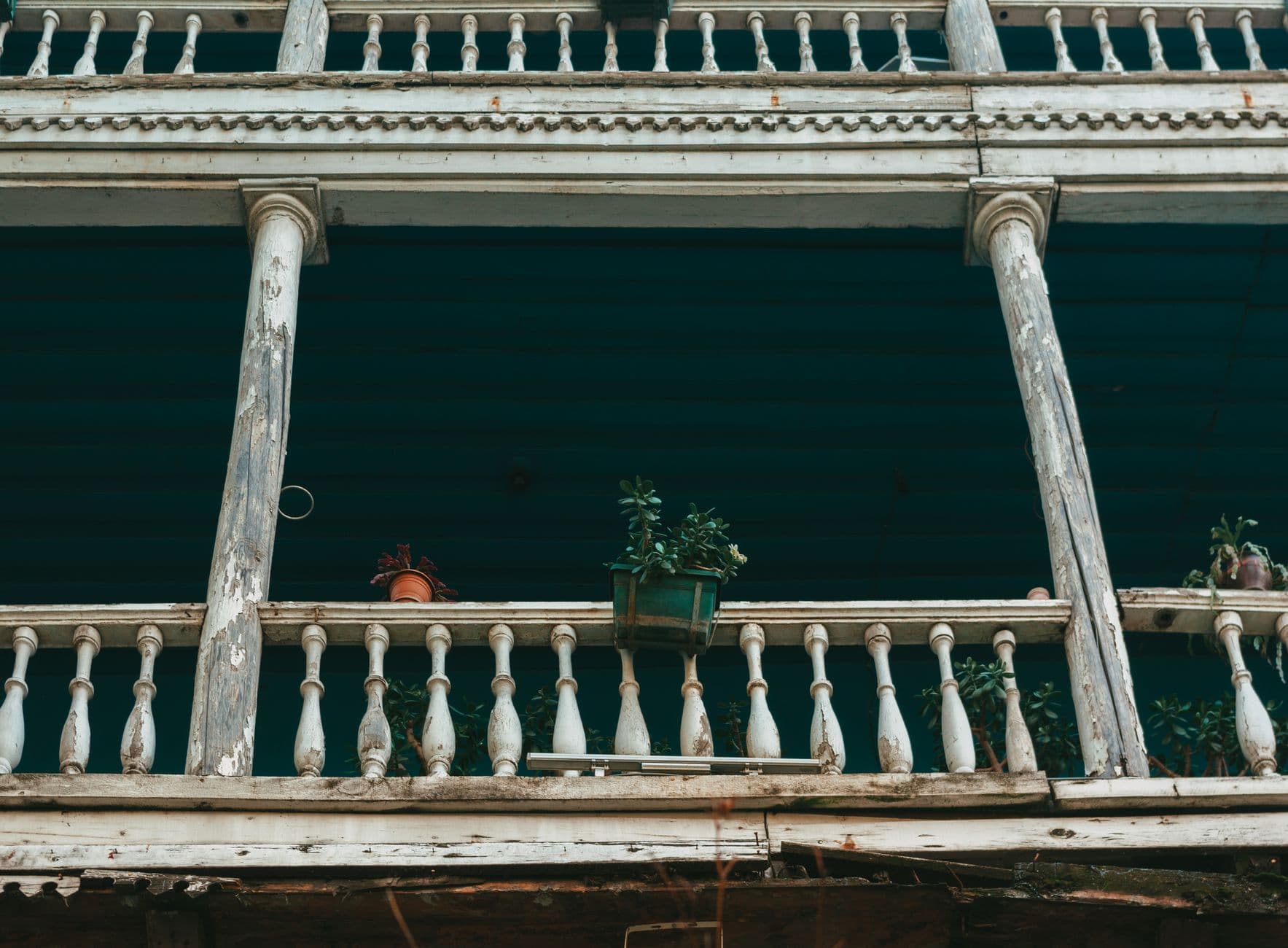 An aged balcony showcasing weathered wood and potted plants, evoking a rustic charm.