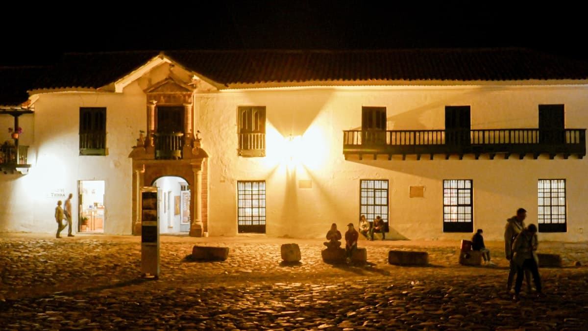 Historic building illuminated at night with people outside.