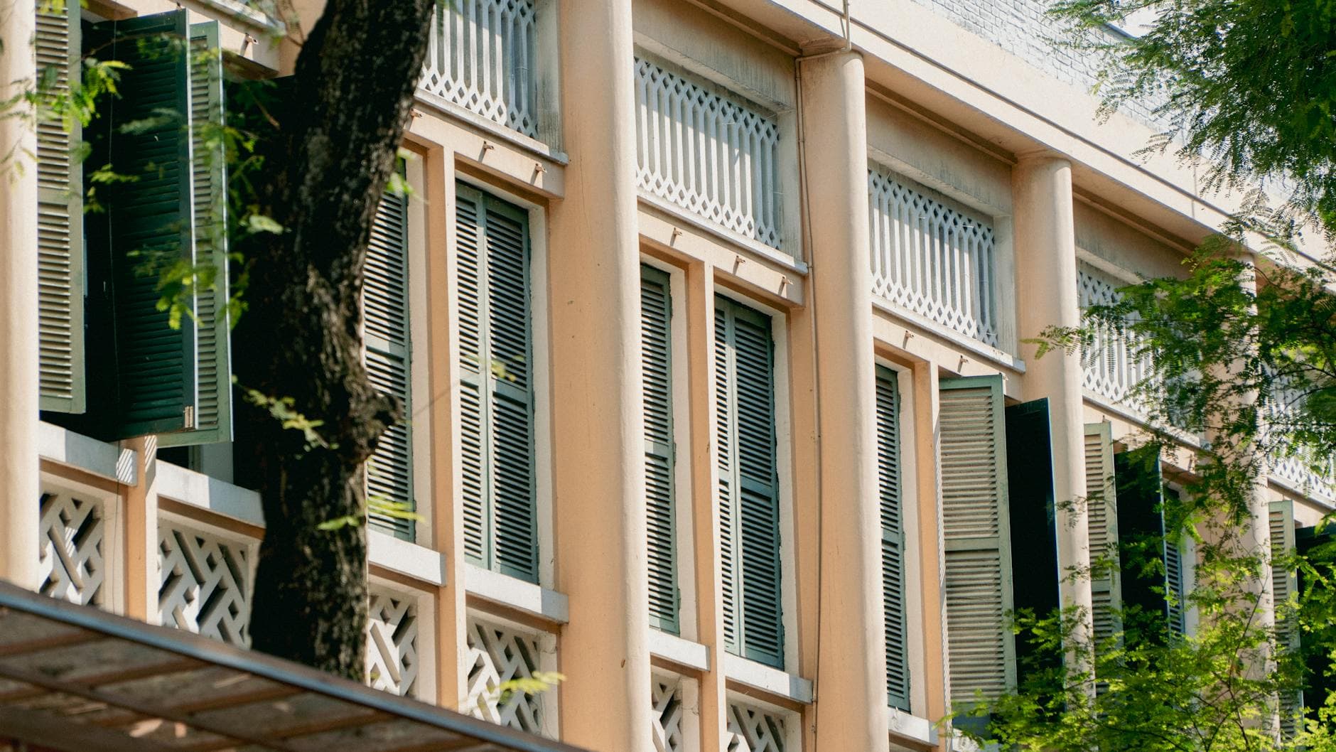 Exterior view of a classic building with green shutters and trees.