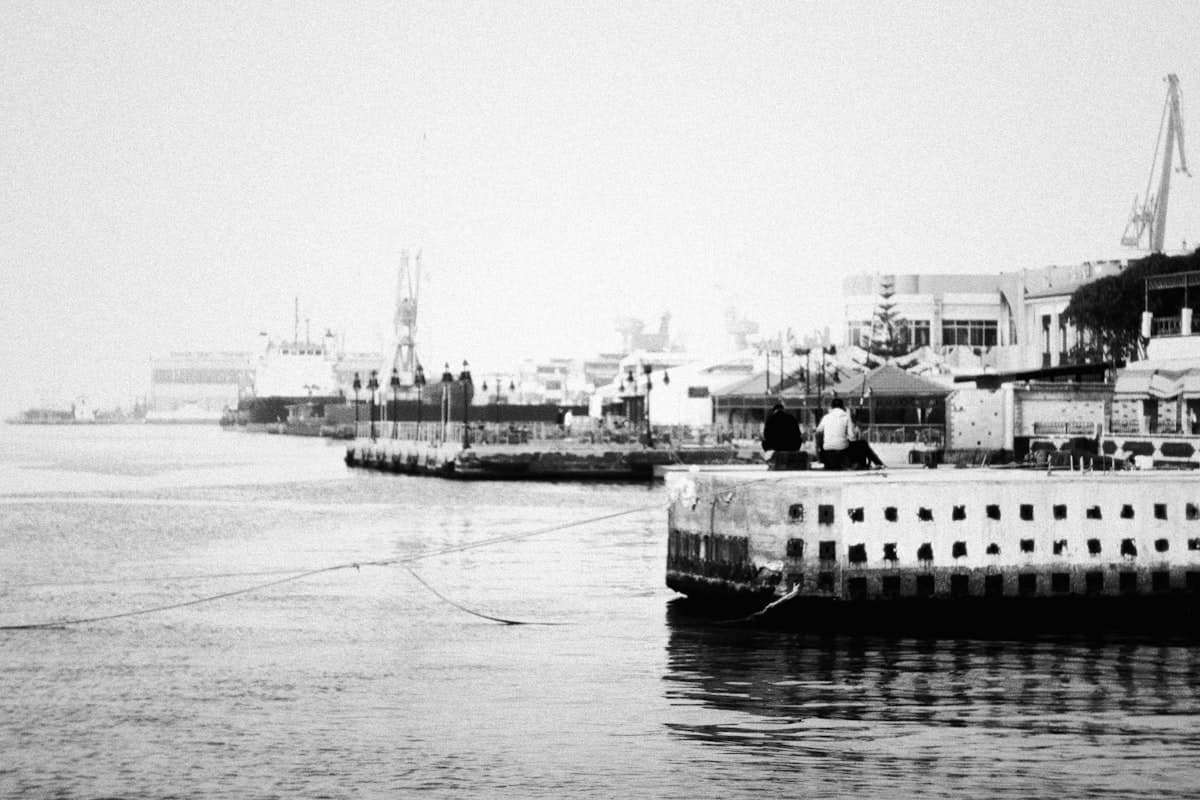 Ships docked in a hazy harbor with buildings in background