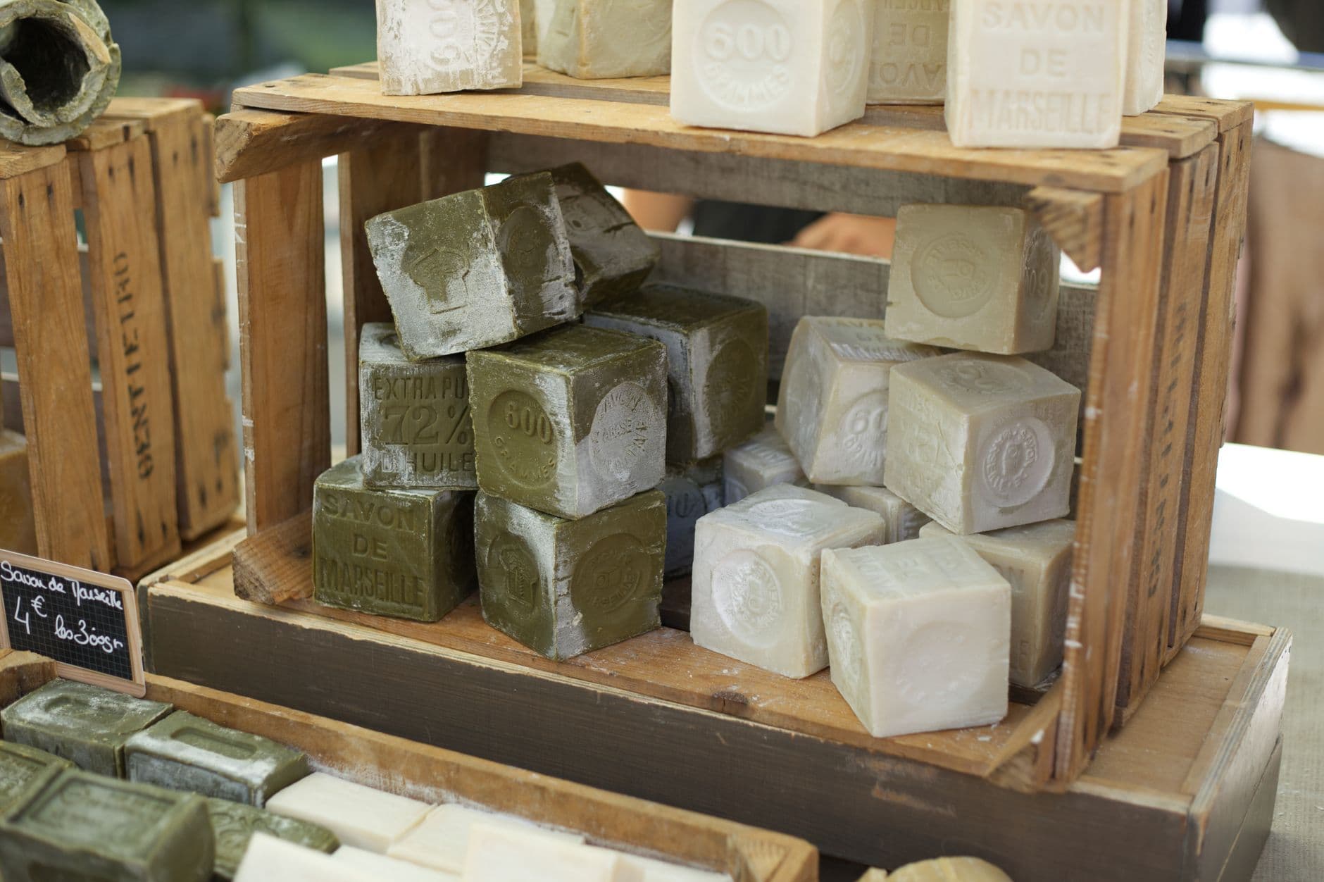Handcrafted soap blocks on wooden shelves at a local market stall.