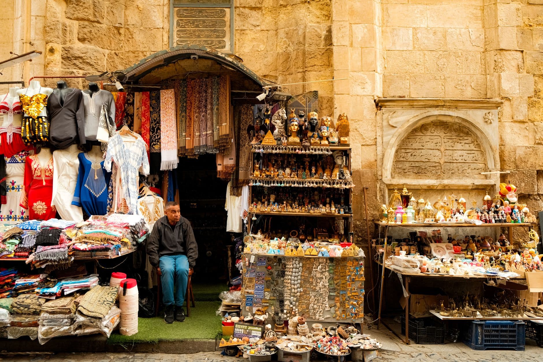 Colorful outdoor market stall with traditional souvenirs and clothing. Captures local culture and commerce.
