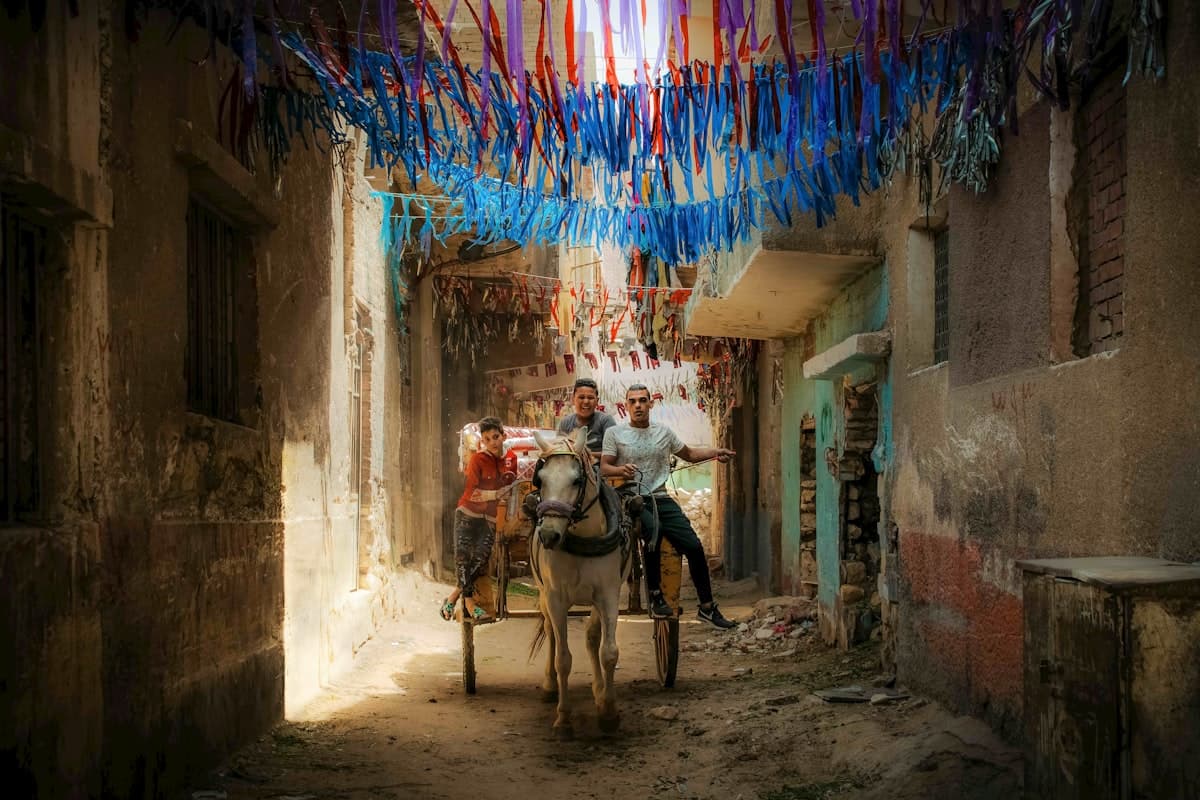 People ride a cart through a decorated alley.