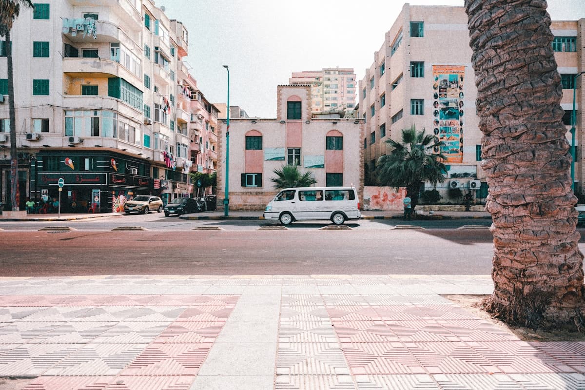 a white van driving down a street next to tall buildings