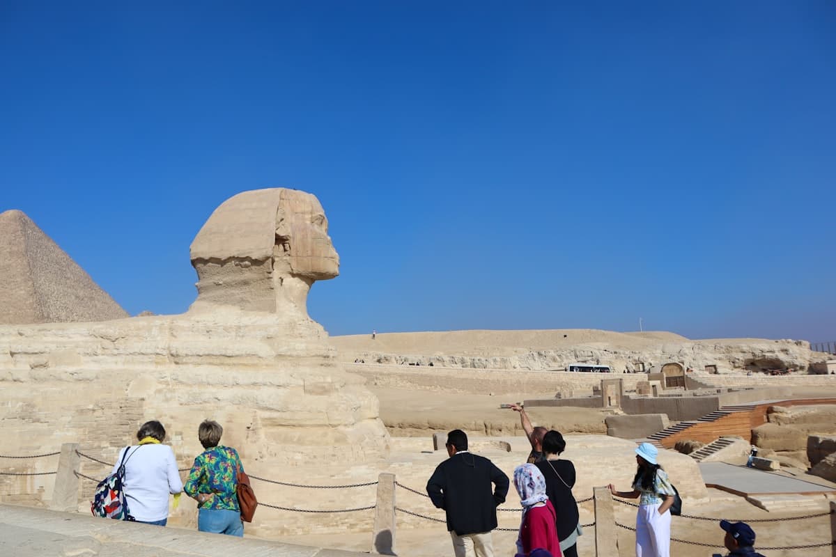 a group of people standing in front of a sphinx